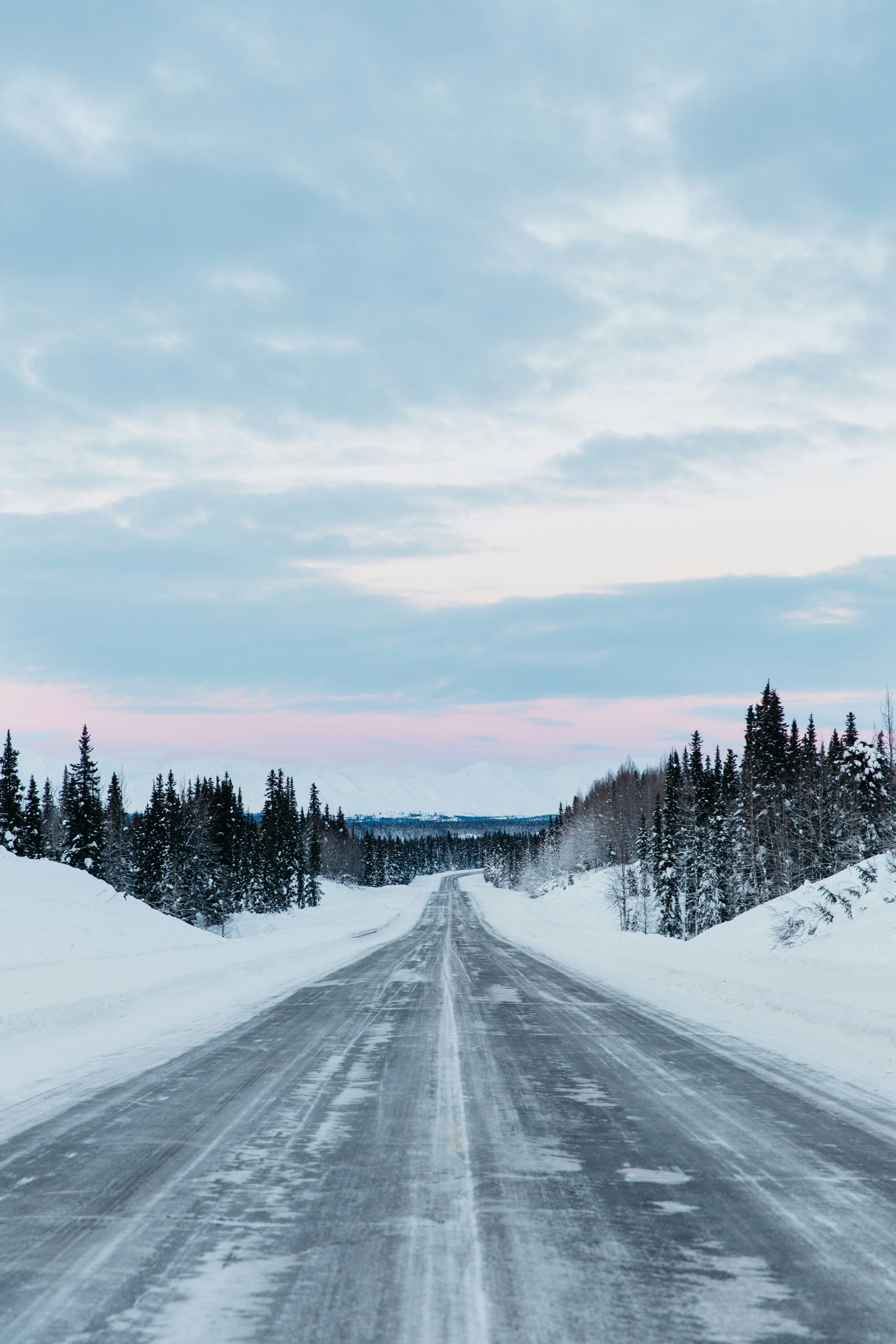 A road crossing a snowy landscape at dawn